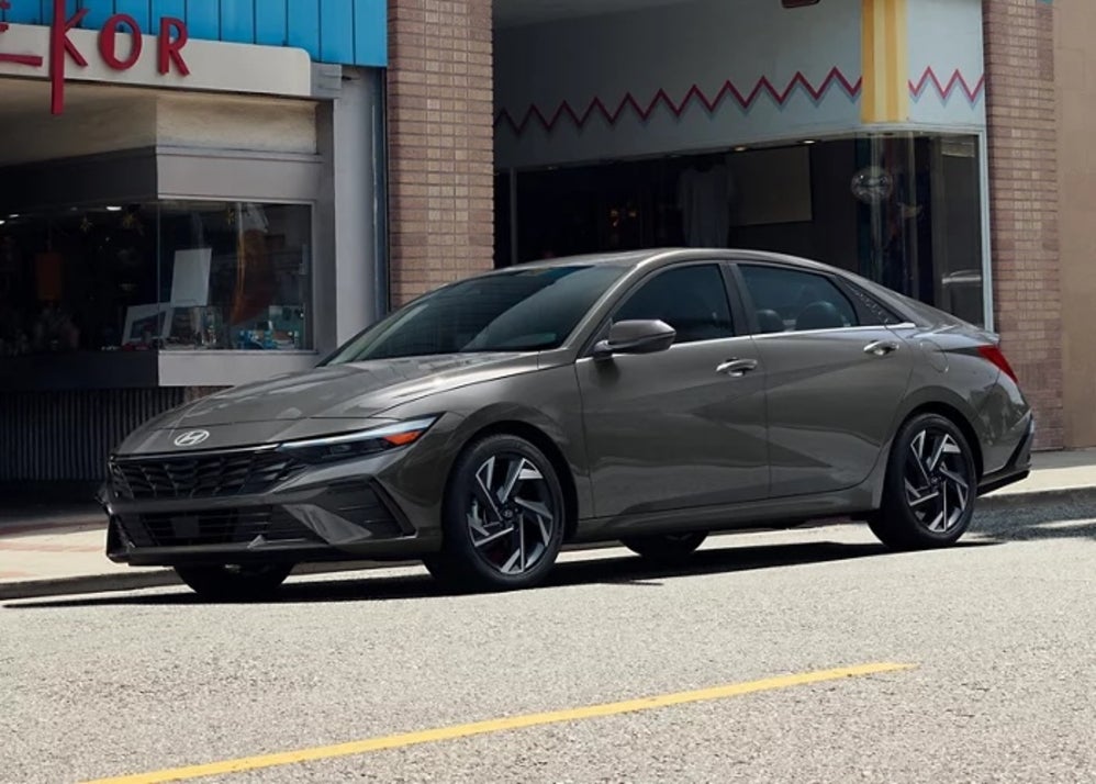 A person walking in front of a silver 2026 Hyundai Sonata at a city crosswalk