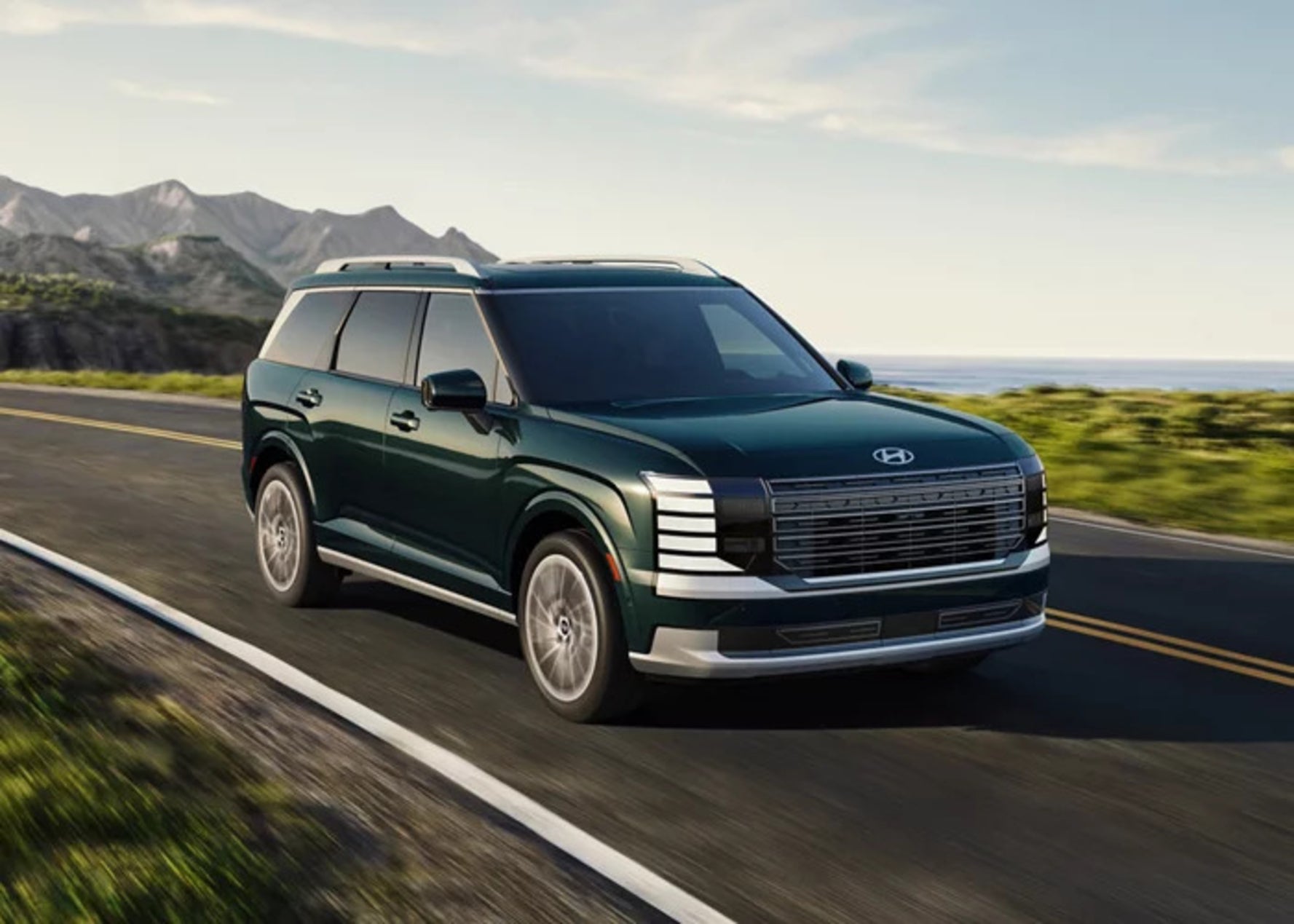 A dark green 2026 Hyundai Palisade SUV driving down a coastal road