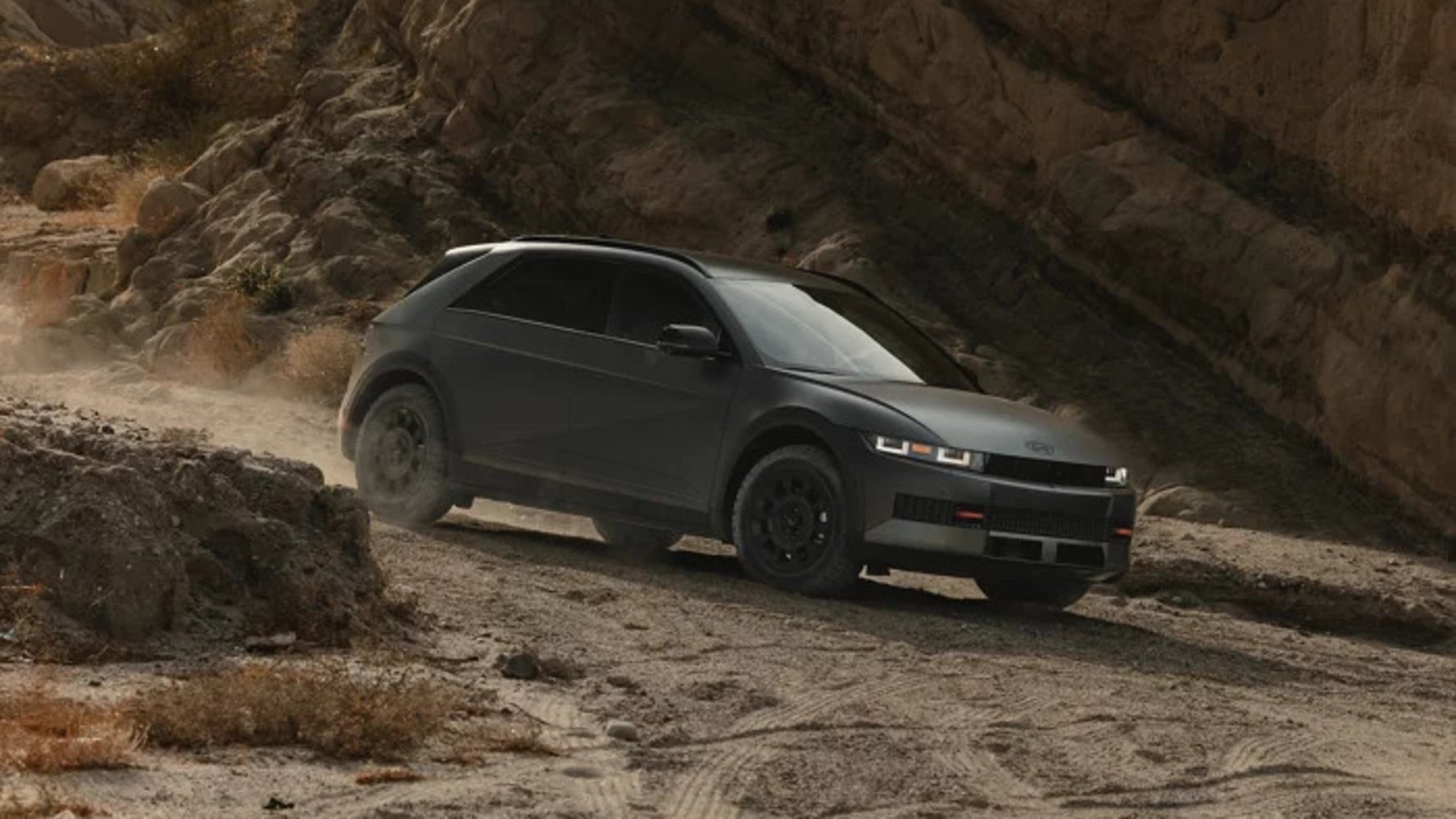 A dark gray 2026 Hyundai Ioniq 5 driving down a dusty mountain path