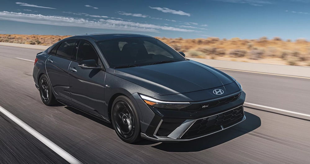 A gray 2026 Hyundai Elantra driving down a road through the desert