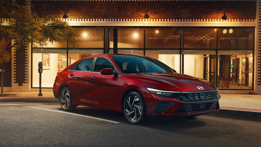 A red 2026 Hyundai Elantra sedan parked in front of an art gallery