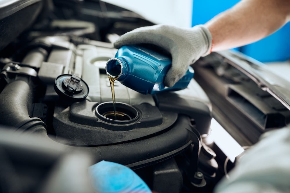 A mechanic pouring engine oil into a vehicle’s engine